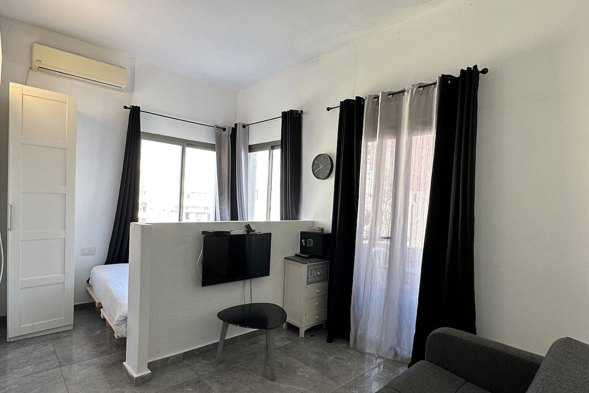 Une pièce de taille modeste comprenant un lit, un bureau, une chaise, un canapé et une fenêtre.