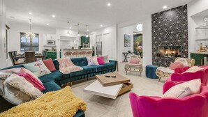 Een moderne woonkamer met een bank, stoelen, een salontafel en een open haard.