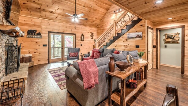 Ein gemütliches Holzblockhaus-Interieur mit Kamin, Treppe und einer bequemen Sitzecke.