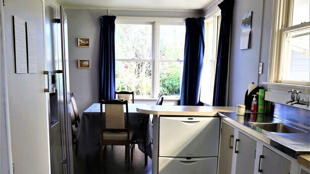 A compact kitchen with a dining table, chairs, and a refrigerator.