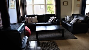 A living room with a black leather sofa, a coffee table, and a fireplace.