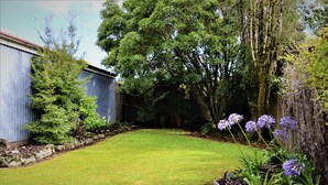 A well-maintained garden with a lawn, flowering plants, and a wooden fence.