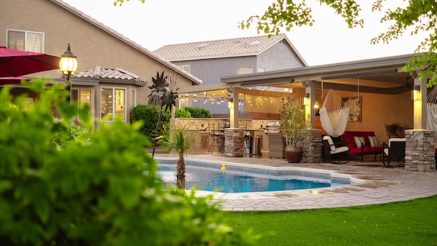 Un patio trasero con piscina, cocina exterior y zona de estar.
