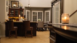 Una cocina con barra, sillas de madera, una mesa de comedor y una vela en la encimera.