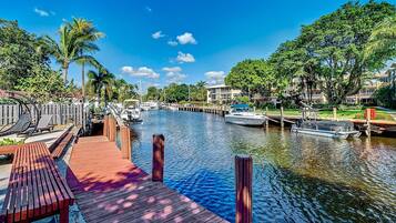 A marina with boats docked, a wooden deck, and a clear blue sky.