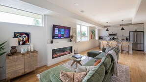 A modern living room with a fireplace, green sofa, and a flat-screen TV mounted on the wall. - New townhome with private rooftop deck and beautiful Mountain Views, 5 min to DU (Denver)