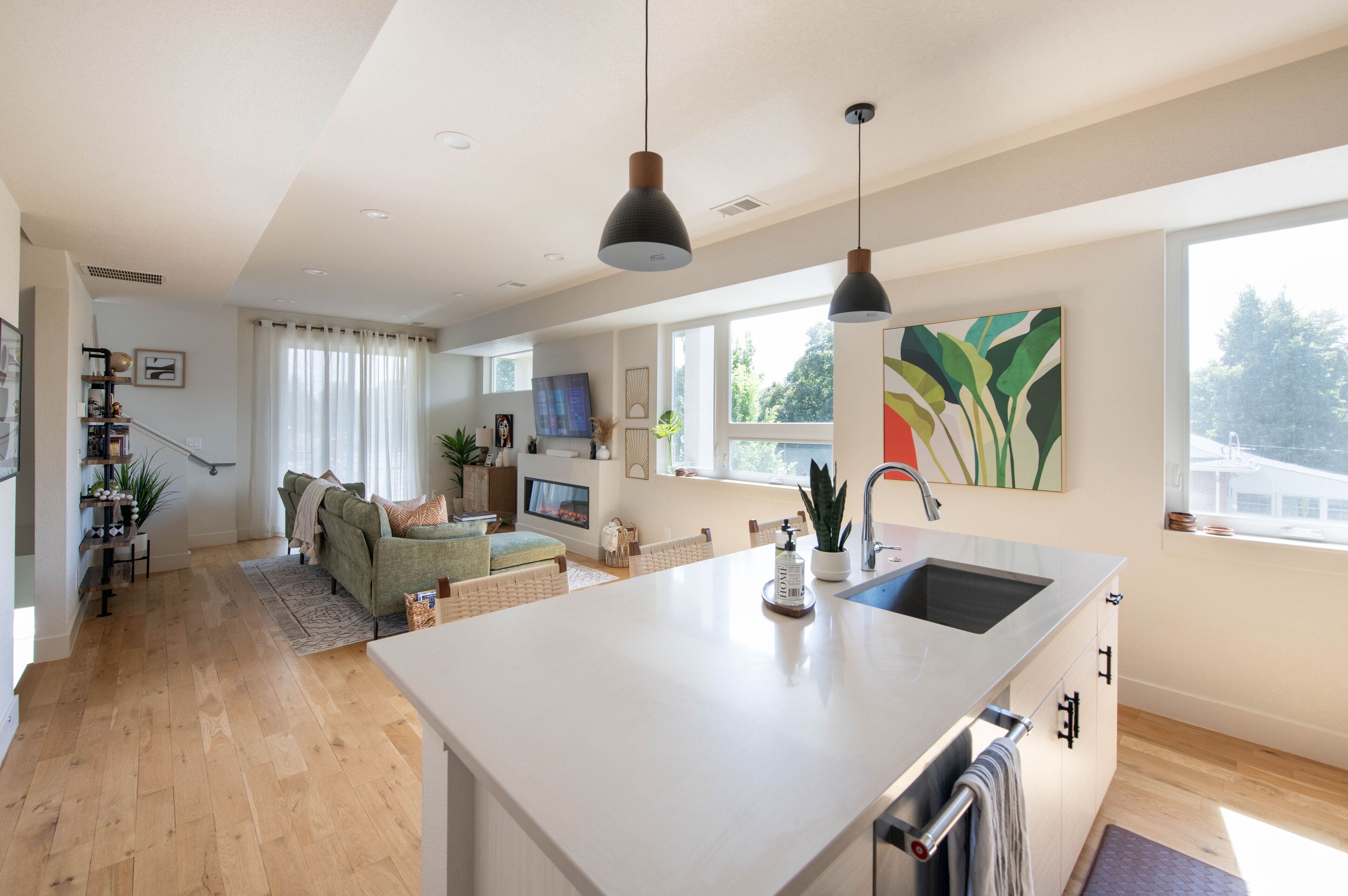 Una cocina moderna con una isla grande, un comedor con sofá y una sala de estar con televisor.