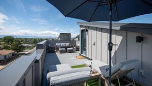A rooftop terrace with a large umbrella, outdoor seating, and a view of the surrounding neighborhood. - New townhome with private rooftop deck and beautiful Mountain Views, 5 min to DU (Denver)