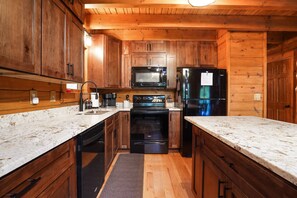 A compact kitchen with wooden cabinets, a microwave, a stove, and a refrigerator.