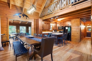 A spacious wooden cabin with a large dining area, kitchen, and a loft bedroom. - Explorer Lodge | Hocking Hills, Theatre Room (Logan)