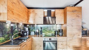 A modern kitchen with wooden cabinetry, a built-in oven, and a coffee station. - Cozy home in Bad Wünnenberg with WiFi (Bad Wünnenberg)