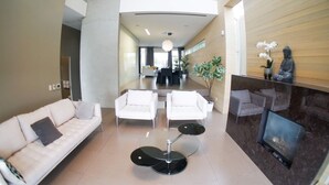 A modern lobby with a reception desk, seating area, and a large column. - Luxury House (Vancouver)