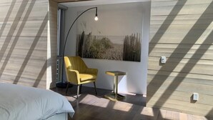 A modern bedroom with a bed, a yellow chair, a small table, and a wall-mounted lamp. - Luxury House (Vancouver)