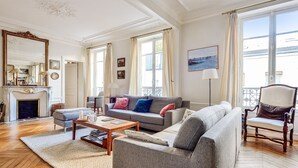 Een ruime woonkamer met een open haard, een groot raam en een balkon.