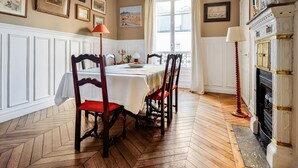 Een eetkamer met een tafel gedekt voor vier personen, omringd door houten stoelen met rode kussens.