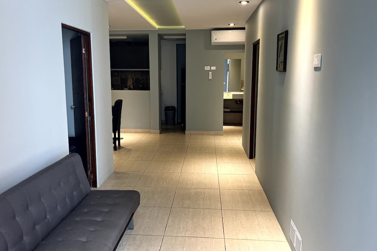 A modern hallway with a grey sofa, a tiled floor, and recessed lighting.