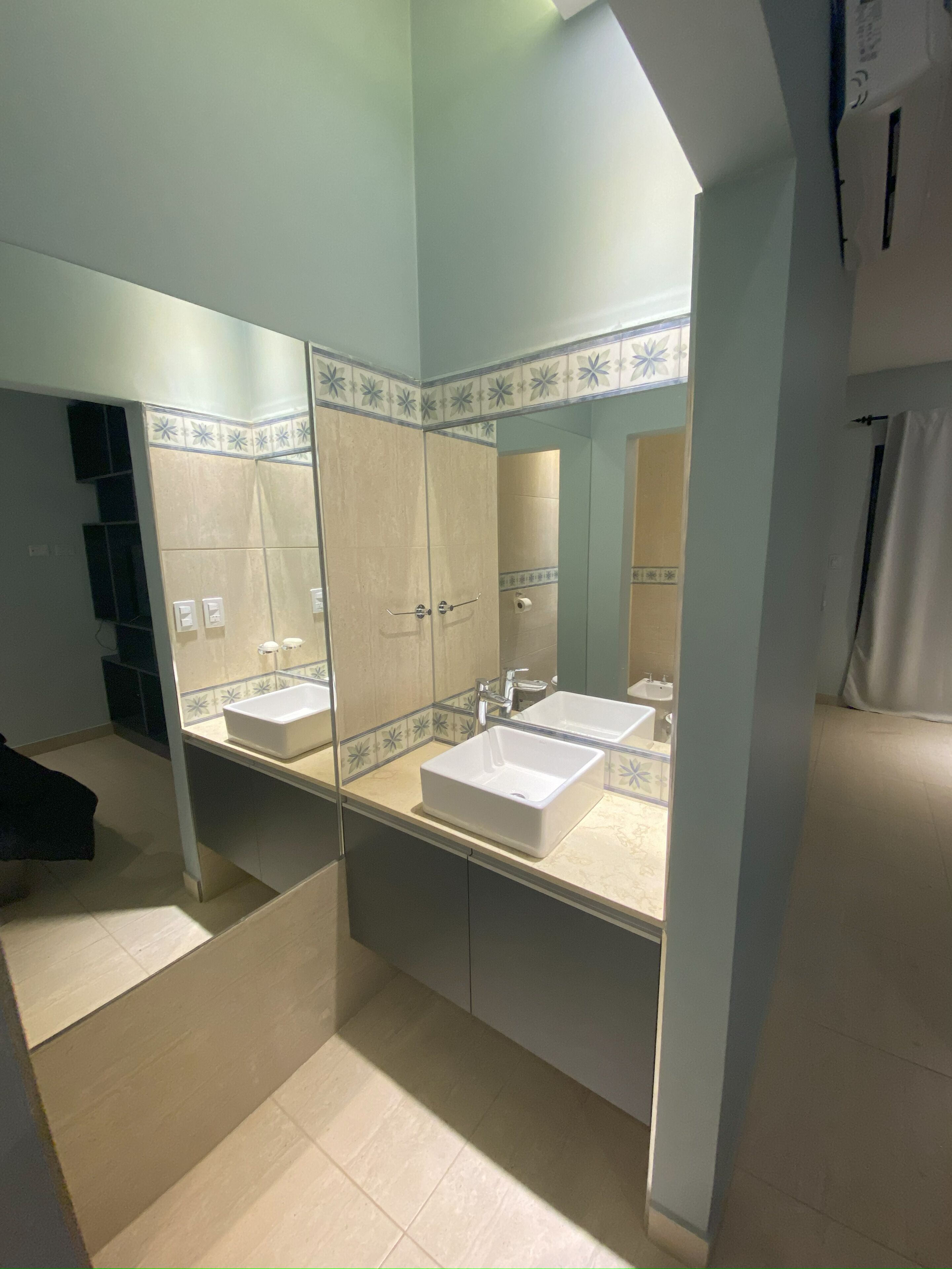 A bathroom with two sinks, a large mirror, and a shower area.