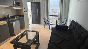 A compact living space with a kitchenette, a dining area, and a sofa. - Departamentos Muskuy (Salta)