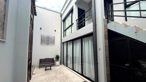 A modern building with a tiled floor, a bench, a potted plant, and a staircase. - Departamentos Muskuy (Salta)