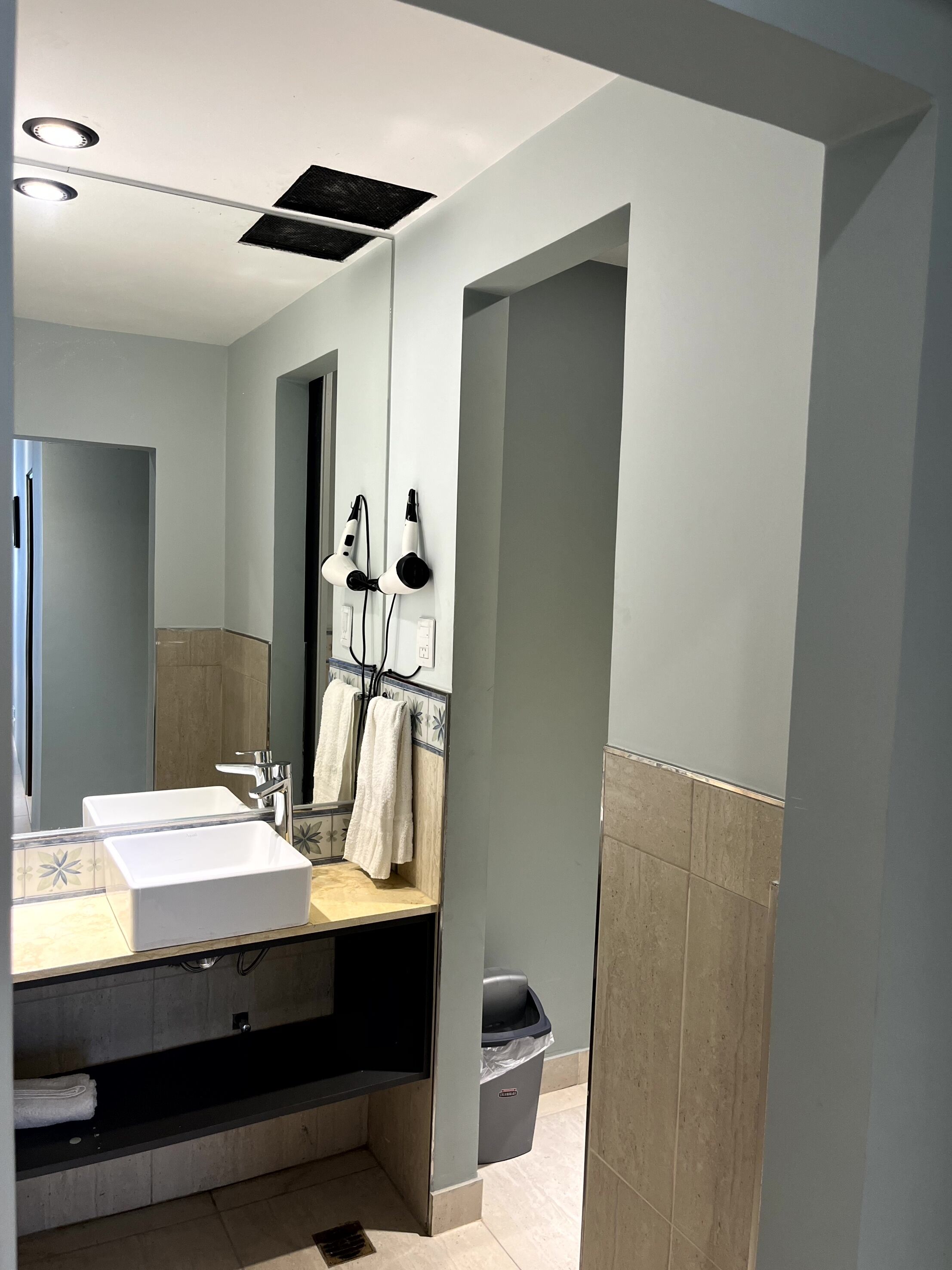 A modern bathroom with two sinks, a large mirror, and a towel rack.