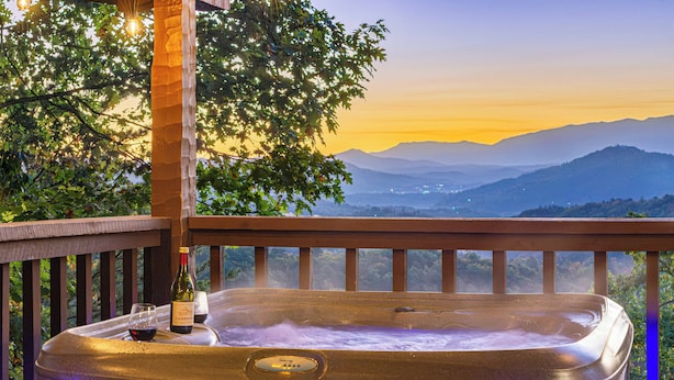 A hot tub with a view of mountains and a tree in the background.