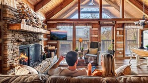 A cozy living room with a stone fireplace, wooden ceiling, and a television.