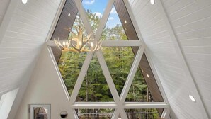 A modern interior with a triangular ceiling structure and a chandelier. - Sky-High A Frame Retreat Hottub & EV charging (Beech Mountain)