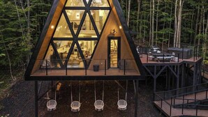 A modern, triangular wooden cabin with large windows, surrounded by a forest. - Sky-High A Frame Retreat Hottub & EV charging (Beech Mountain)
