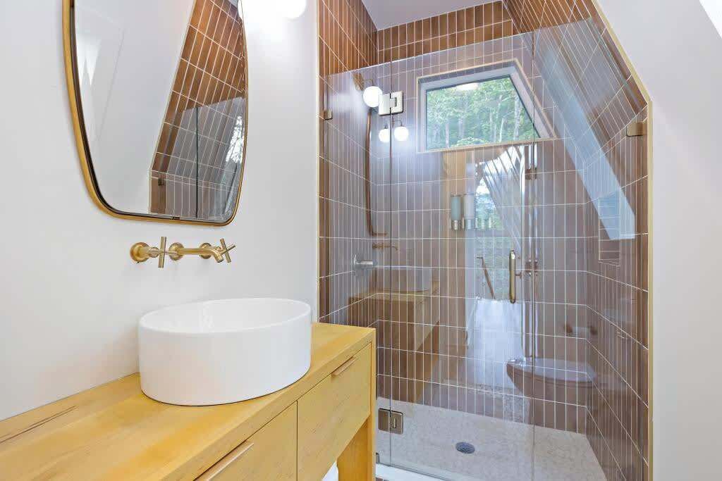 A modern bathroom with a white sink, a large mirror, and a shower area with a glass door.