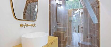 A modern bathroom with a white sink, a large mirror, and a shower area with a glass door.