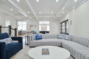 A modern living room with a sectional sofa, a round coffee table, and a blue armchair. - Ultra North Beach, Ventnor family beach house (Ventnor City)