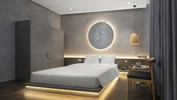A modern bedroom with a large bed, a circular wall art piece, a hanging light fixture, and a wooden chair. - Jacayl Hotel - Ha Dong (Hanoi)