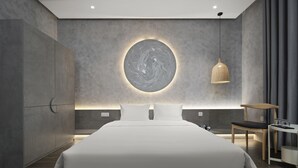 A modern bedroom with a large bed, a circular wall art piece, a hanging pendant light, and a small table with a chair. - Jacayl Hotel - Ha Dong (Hanoi)