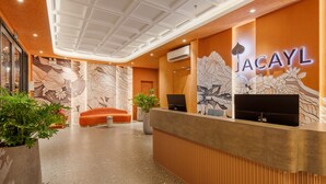 A reception area with a modern design, featuring a reception desk, seating area, and a large floral mural on the wall. - Jacayl Hotel - Ha Dong (Hanoi)