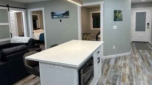 Una cocina moderna con una isla central, armarios blancos y horno empotrado.