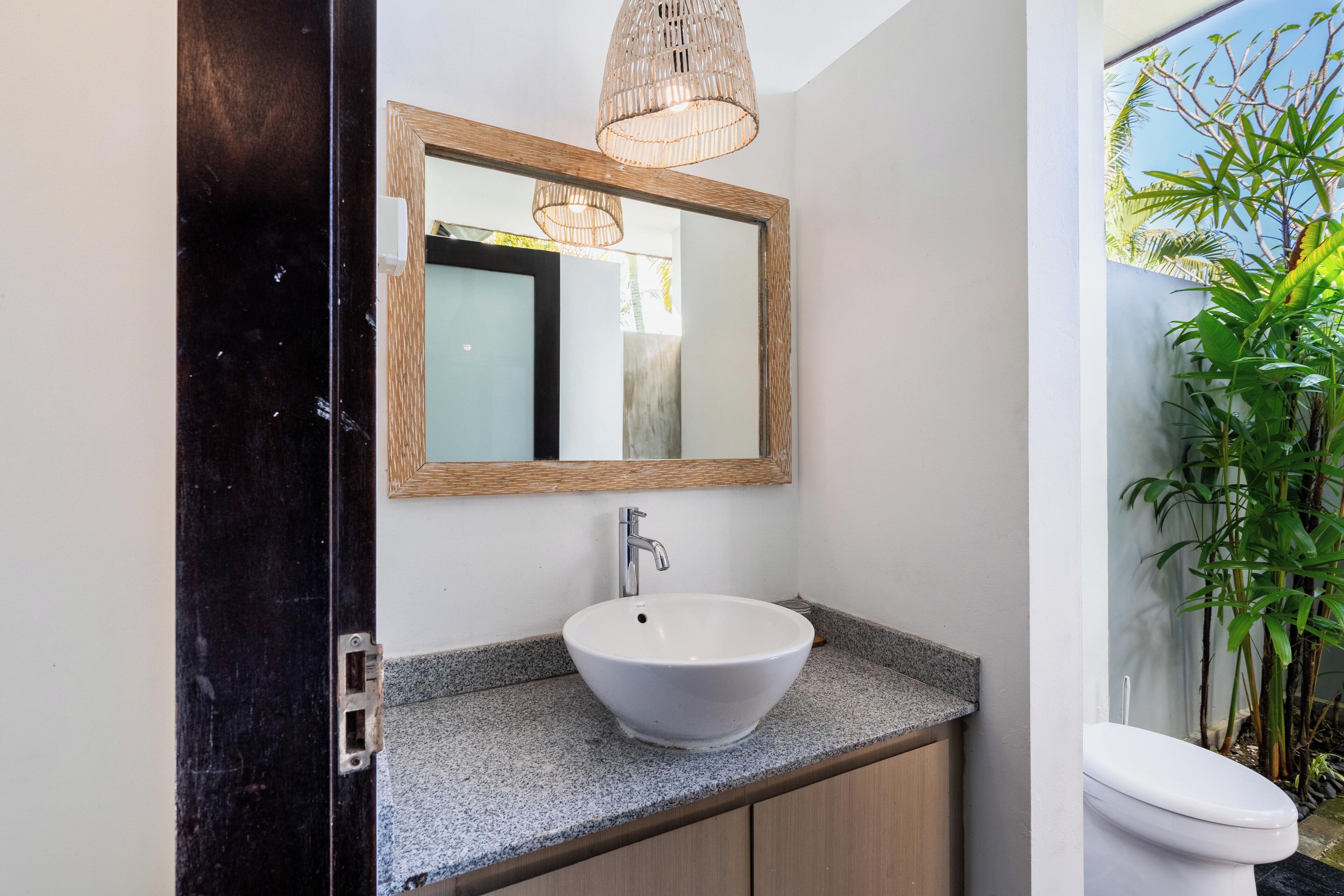 A bathroom with a white sink, a wooden-framed mirror, and a hanging light fixture.