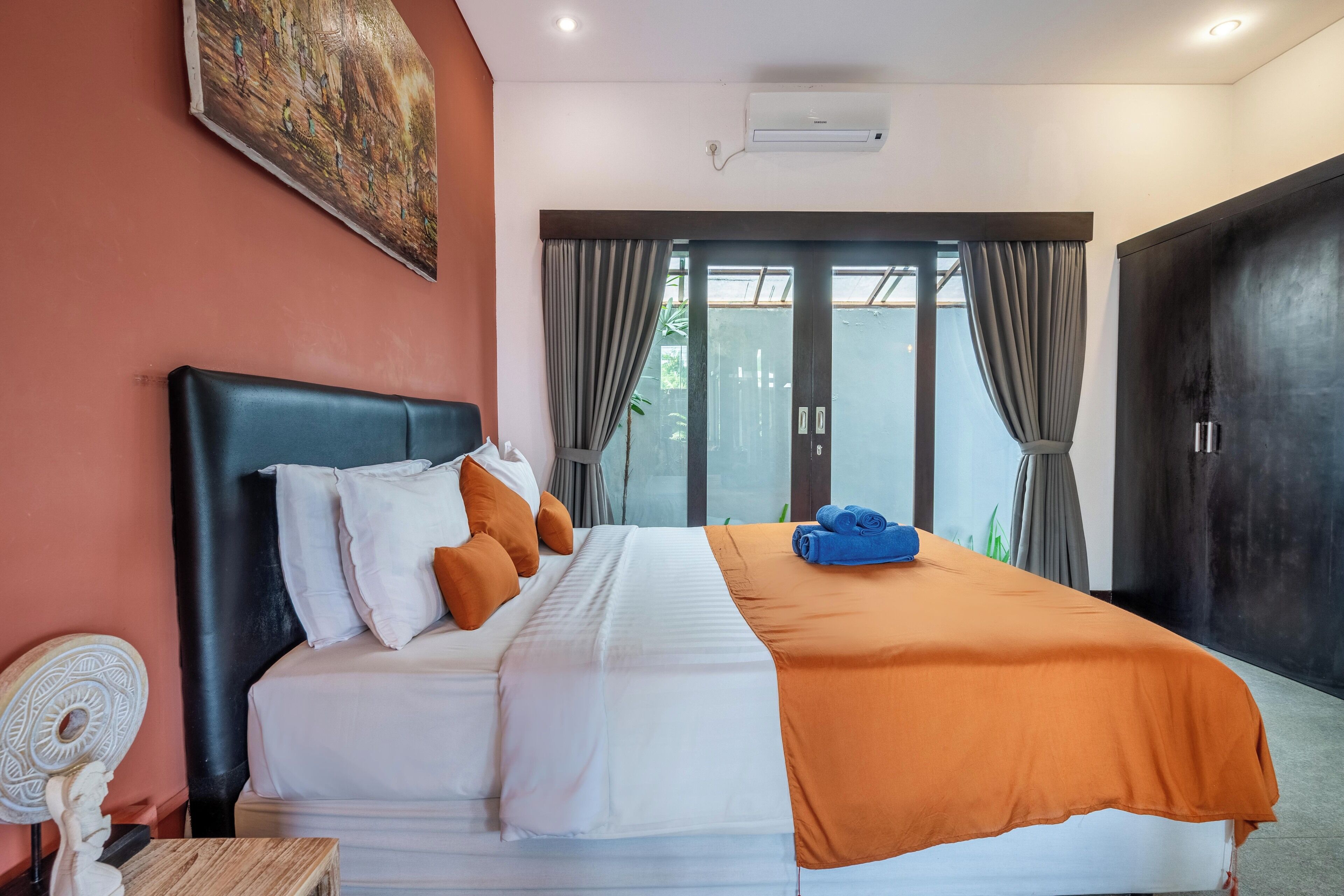 A neatly made bed with a white and orange bedspread, a headboard, and several pillows.