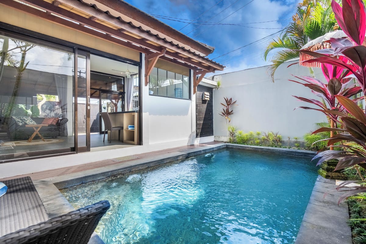 Une maison moderne dotée d’une piscine, de grandes portes vitrées et d’un espace patio.