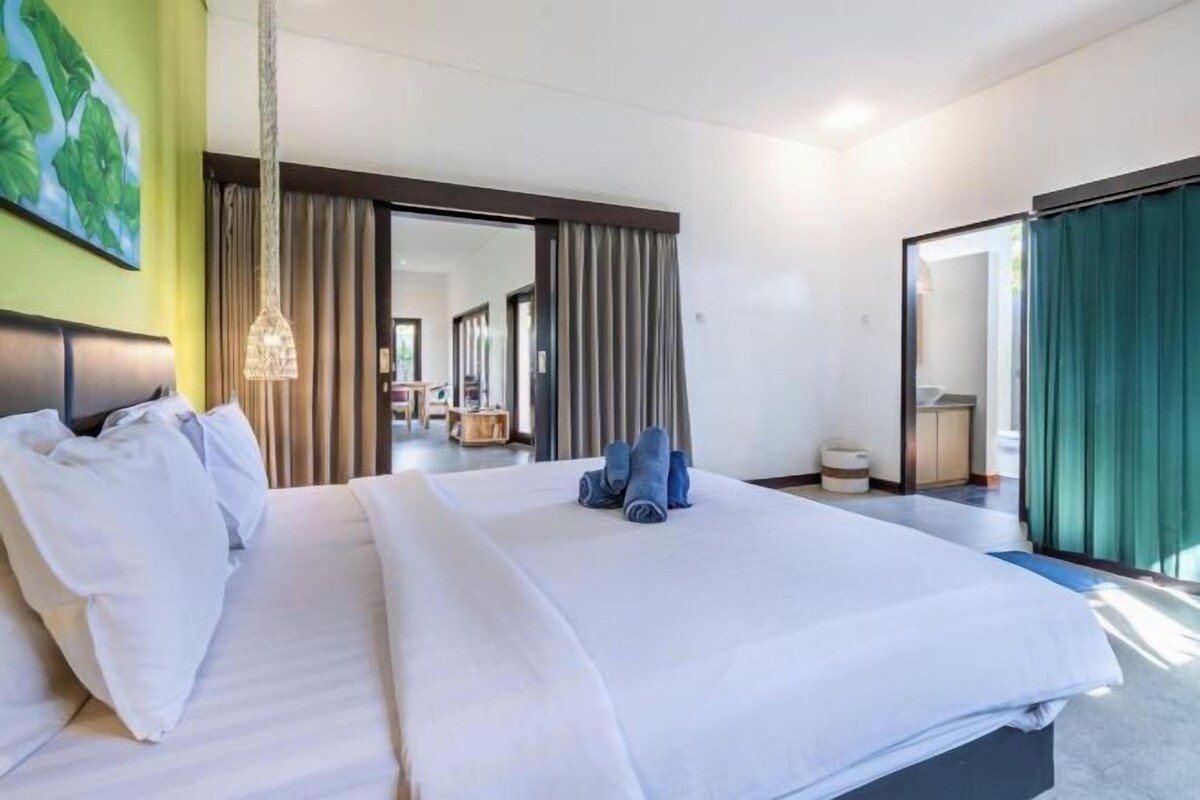 A hotel room with a large bed, a desk, and a view of the hallway.