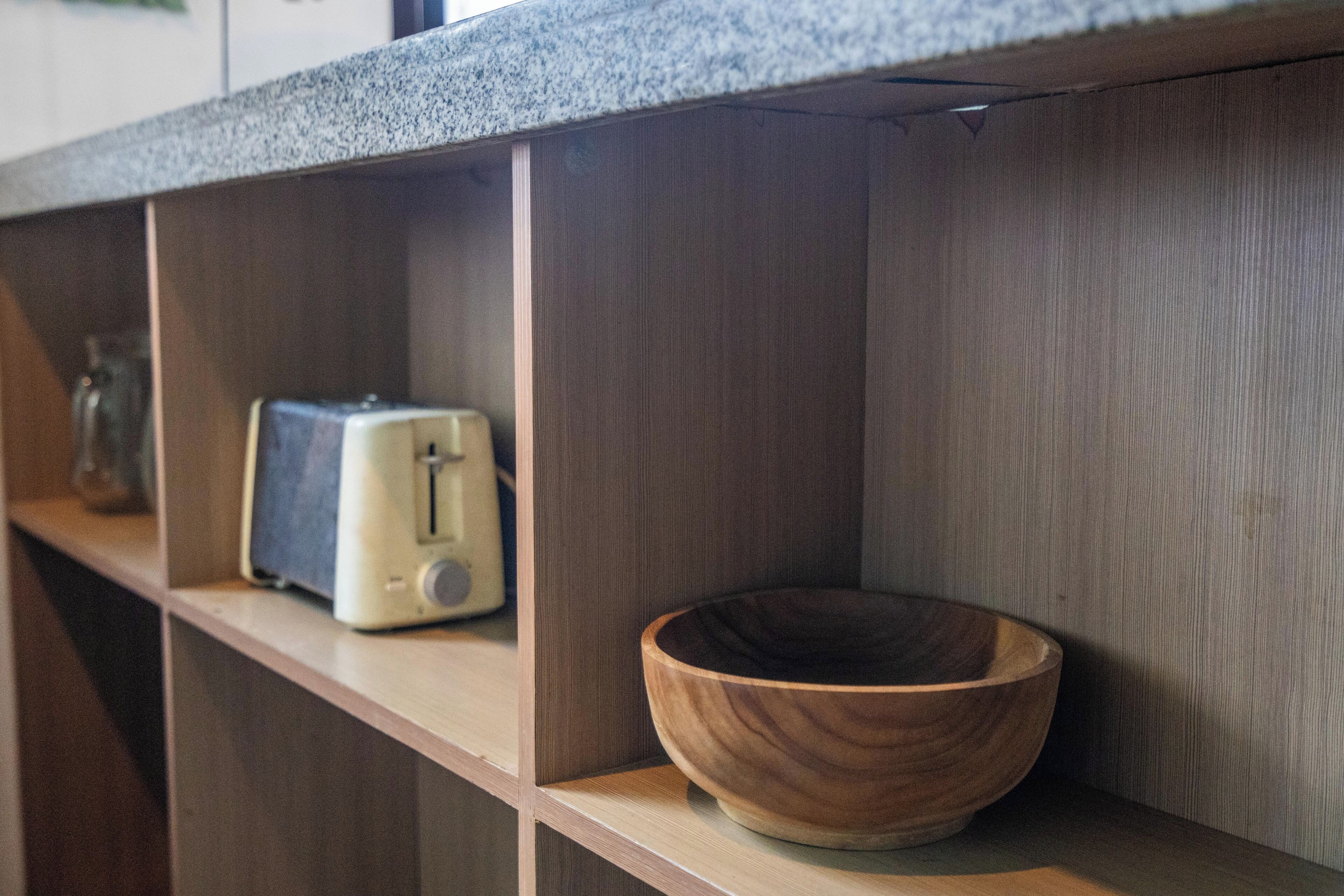 A kitchen shelf with a wooden bowl and a vintage toaster.