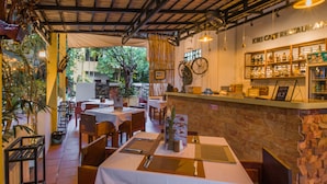 Ein Restaurant mit gedeckten Tischen, einer Theke mit Speisekarte und Blick ins Freie.