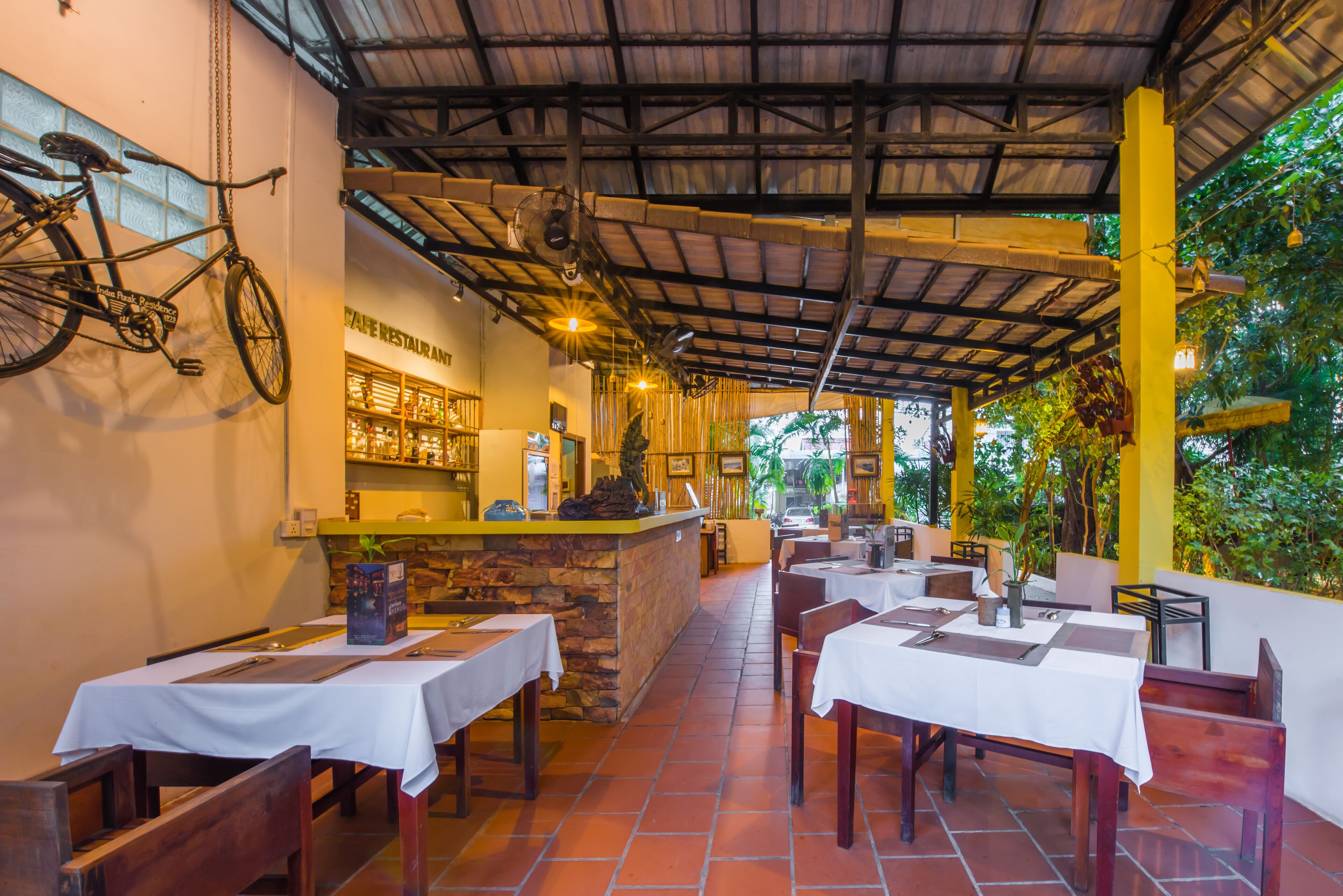 An outdoor restaurant with tables and chairs, a counter, and a bicycle hanging on the wall.