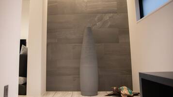 Un pasillo con una gran escultura cilíndrica, una tortuga y un televisor sobre un soporte.