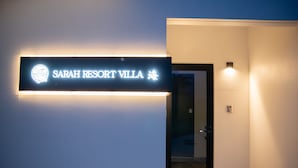 Een bordje voor Sarah Resort Villa, met een modern design en een duidelijke deur die naar de binnenkant leidt.