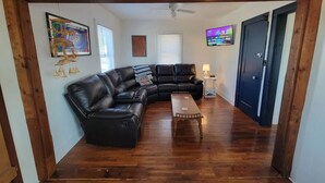 A living room with a black leather sectional sofa, a wooden coffee table, and a ceiling fan.
