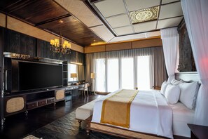 A hotel room with a large bed, a TV, a desk, and a chair.
