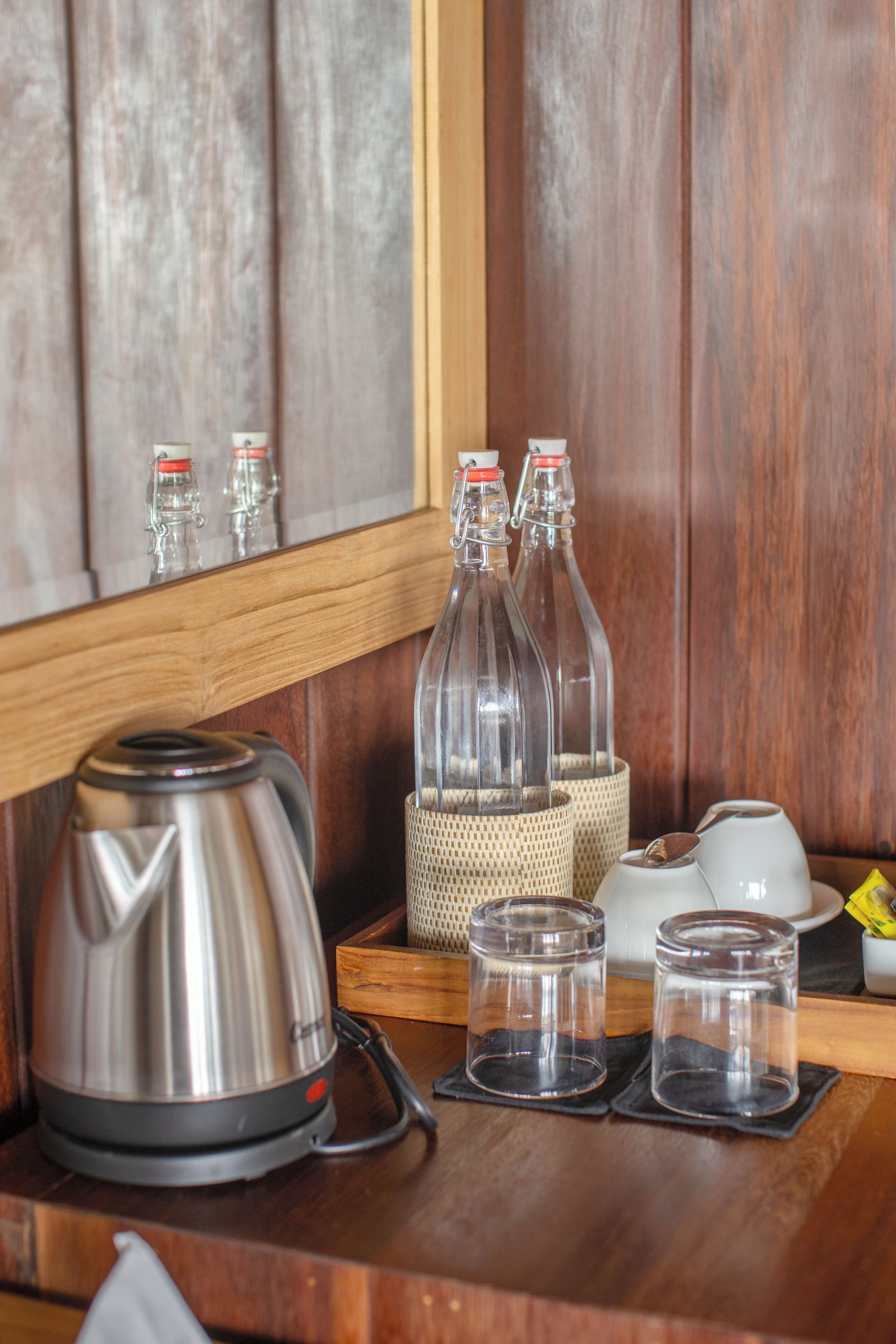 Una encimera de cocina con una tetera, dos botellas de vidrio y dos vasos pequeños.