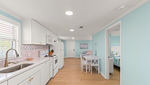Une cuisine moderne avec des meubles blancs, un évier et un coin repas comprenant une table et des chaises.