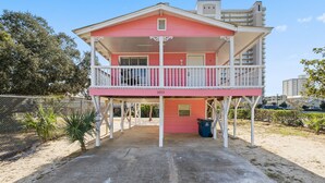 Un bâtiment rose avec un balcon, le numéro « 1013 » sur la façade, et une poubelle à proximité.