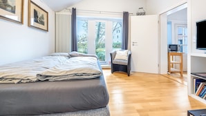 Ein Schlafzimmer mit einem Bett, einem Sessel, einem Fernseher und einem Bücherregal.